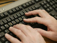 Hands typing on computer keyboard.